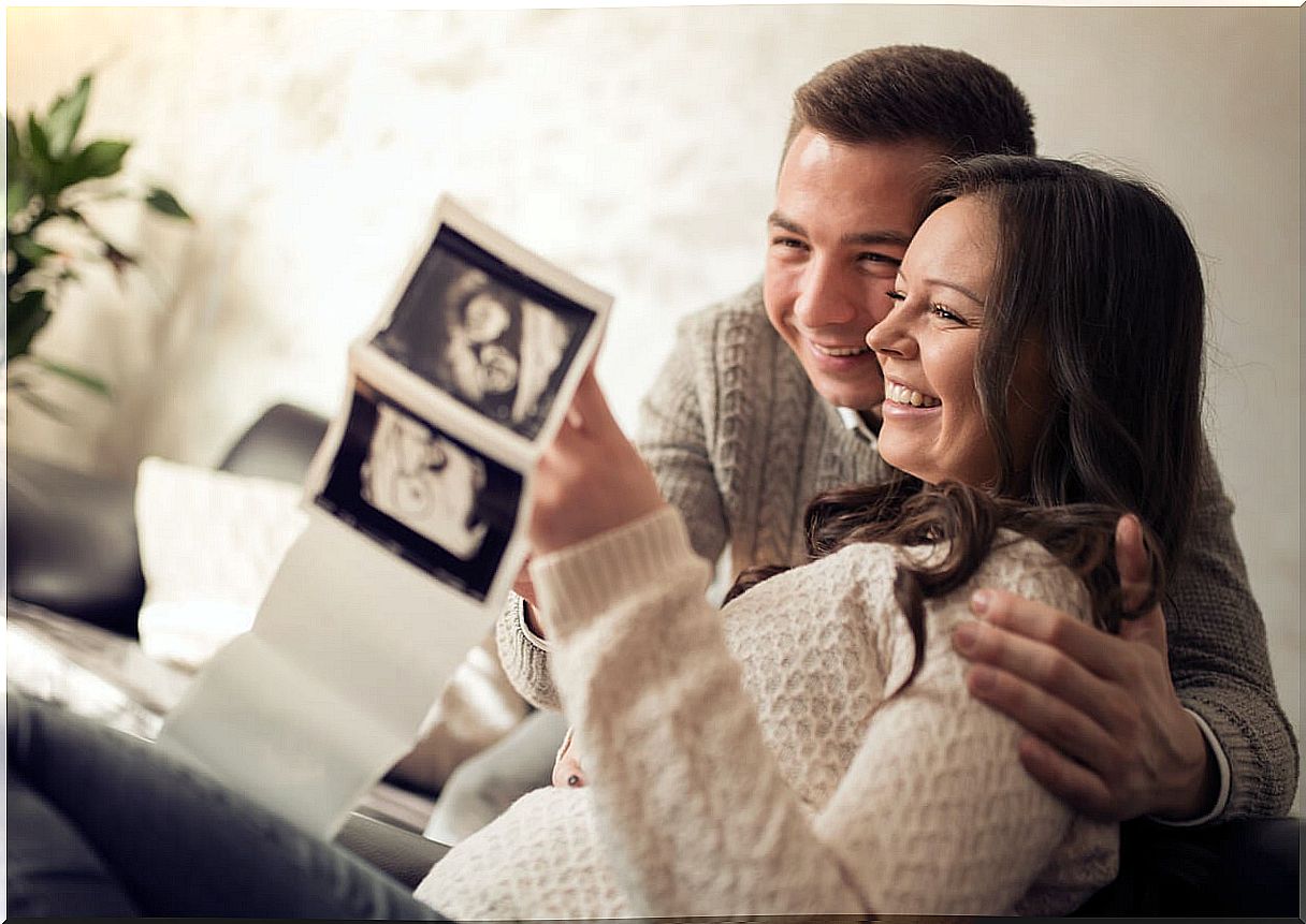 Happy parents looking at their son's ultrasound and thinking of names that start with the letter E.