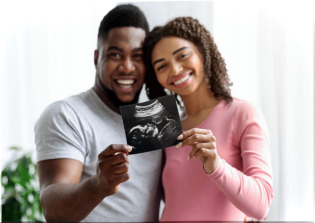 Happy parents with their son's ultrasound in their hands.