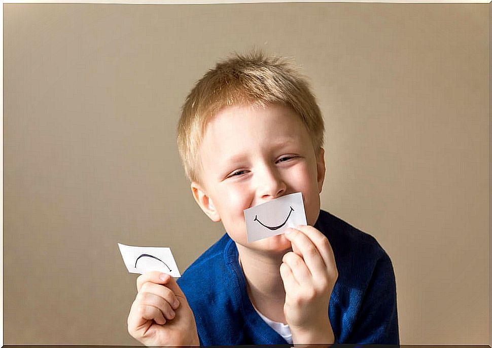 Child doing an activity to work on emotions with one piece of paper that expresses happiness and the other sadness.