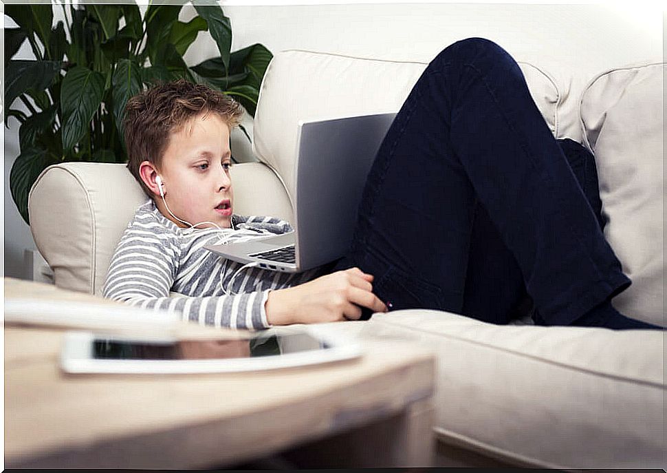 Consensual child watching series on the computer lying on the sofa.