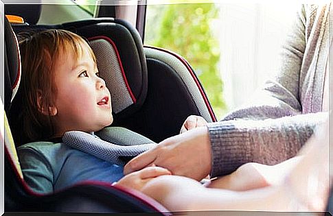 Father tying his son's car seat belt to be able to travel safely