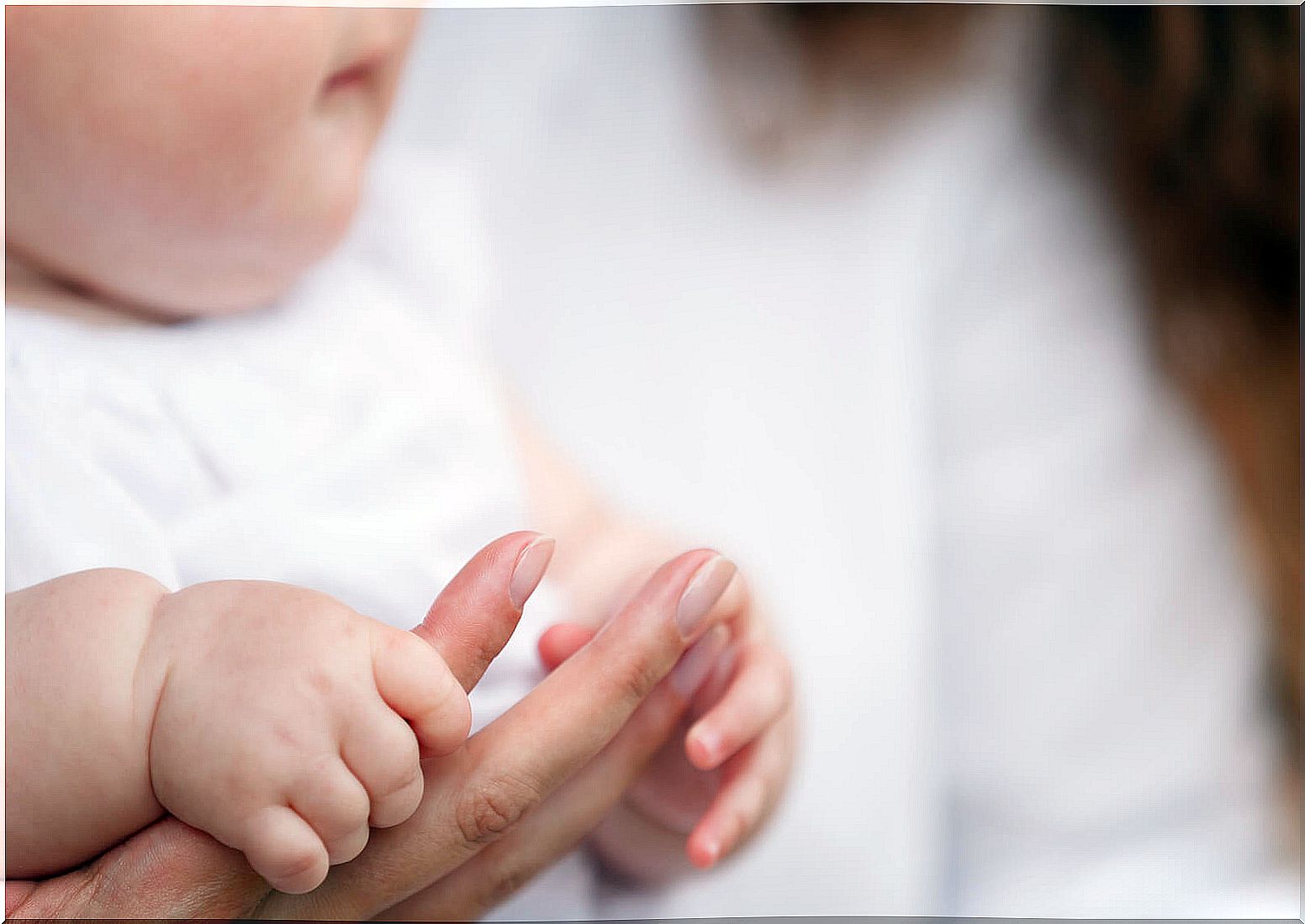 Baby grasping his mother's finger to avoid attachment trauma.