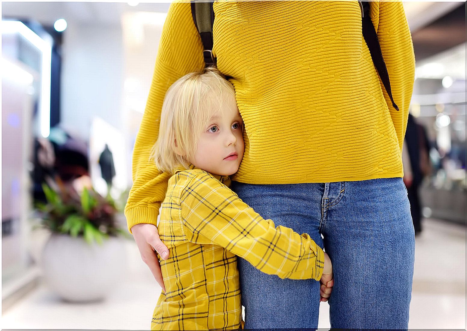 Child hugging his mother's leg.