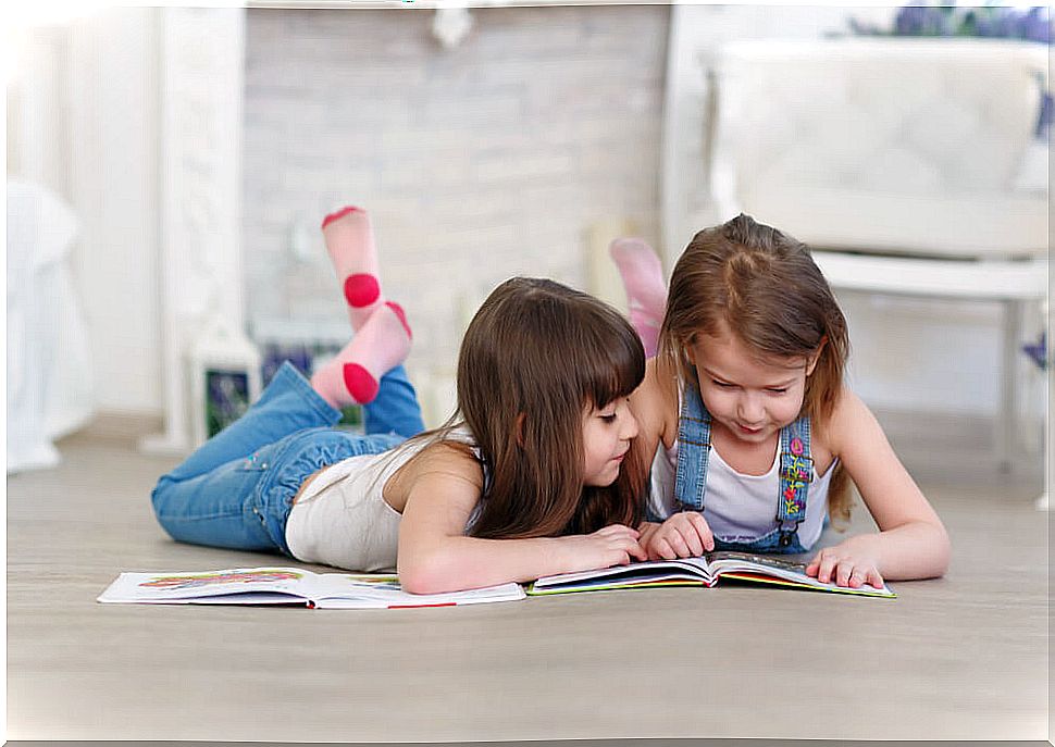 Girls reading children's books lying on the floor to laugh.