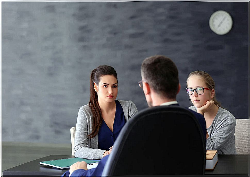 Mother and daughter talking to a teacher to claim an unfair grade.