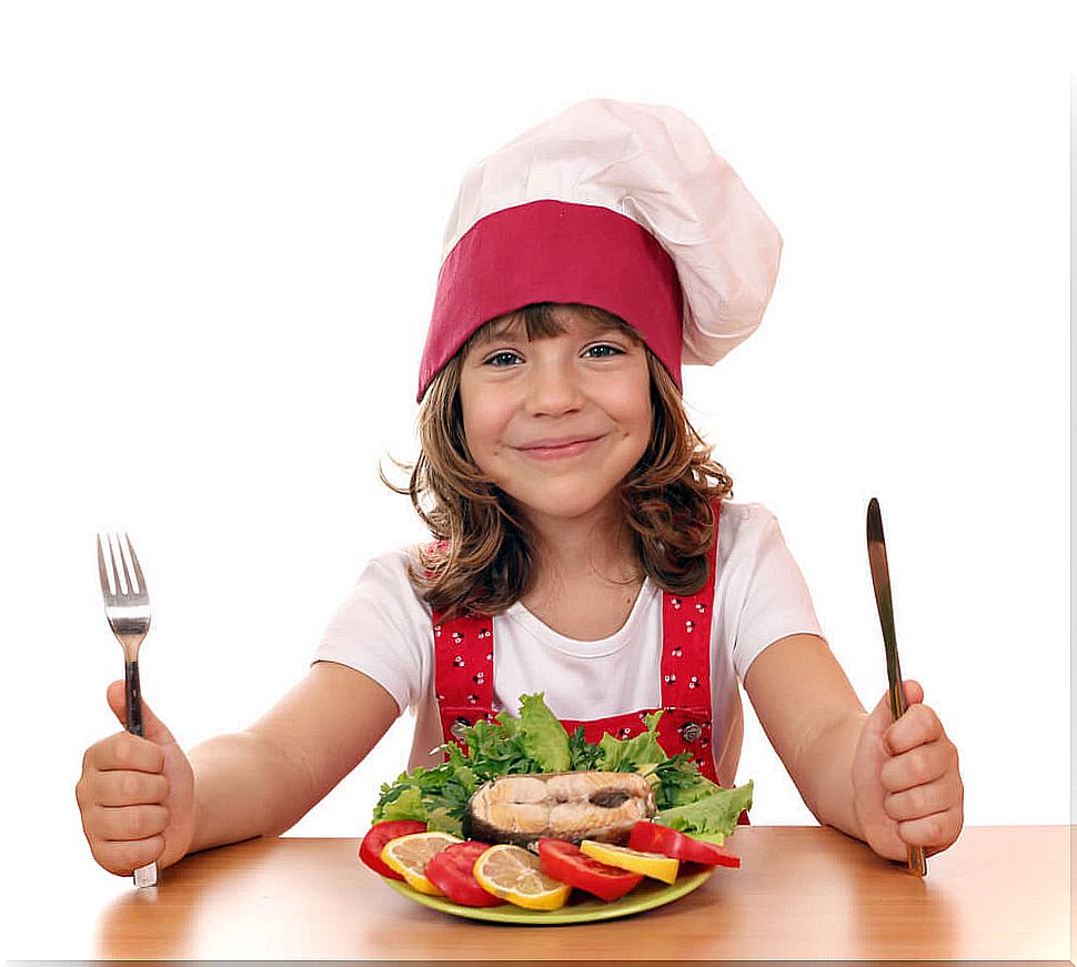 Little girl eating a plate of salmon because she likes fish.