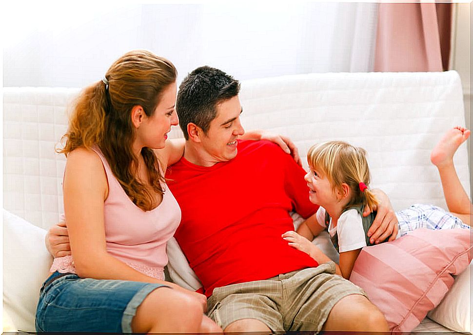 Parents talking to their daughter on the couch.