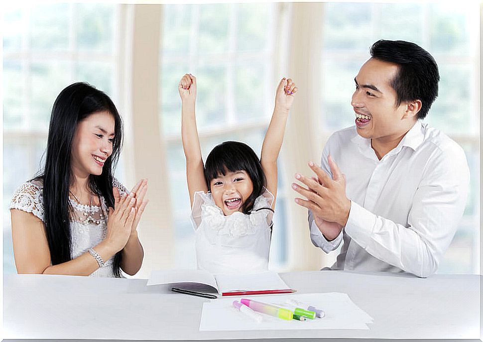 Parents congratulating their daughter for doing her homework well as part of the positive care.