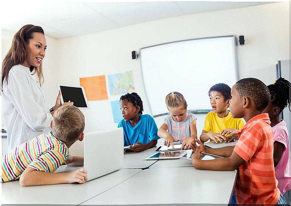 Teacher teaching her students with a tablet in her hand.